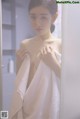 A woman wrapped in a towel standing in front of a mirror.