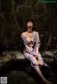 A woman sitting in a hot spring in a stone wall.