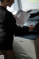 A woman in a business suit is using a printer.