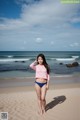 A woman in a pink and blue bikini standing on a beach.