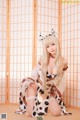 A woman in a cow costume sitting on the floor.