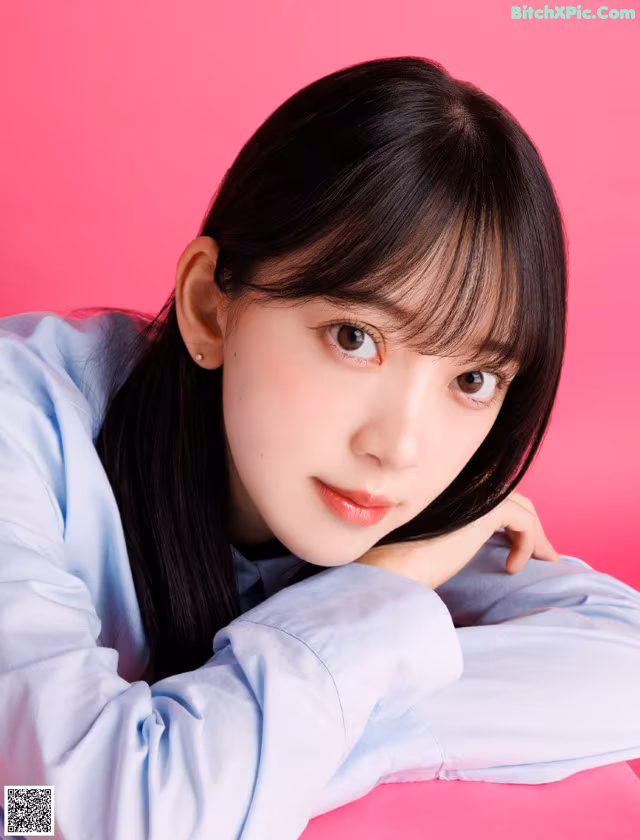 A woman with long black hair wearing a blue shirt.