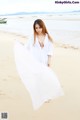 A woman in a white dress standing on a beach.