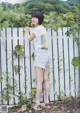 A woman standing in front of a white picket fence.