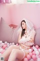 A woman in a white lingerie sitting on a pink couch.